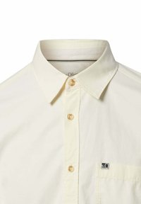 Hellbeiges Hemd mit Kragen und durchgehendem Knopfverschluss, dezent strukturierte Oberfläche und kleinem Logopatch auf der Brusttasche. Klassisches Design.
