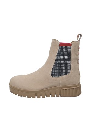 Bottine beige en daim avec semelle épaisse couleur fauve, panneau latéral élastique à carreaux noir et blanc, bordure rouge et languette avec accents rouges à l'arrière.