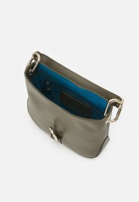 Oliivivärinen nahkakäsilaukku, jossa on sileä pinta, kultaiset yksityiskohdat ja kirkkaan sininen sisustus. Varustettu turvallisella läpällä ja vetoketjupuolella.