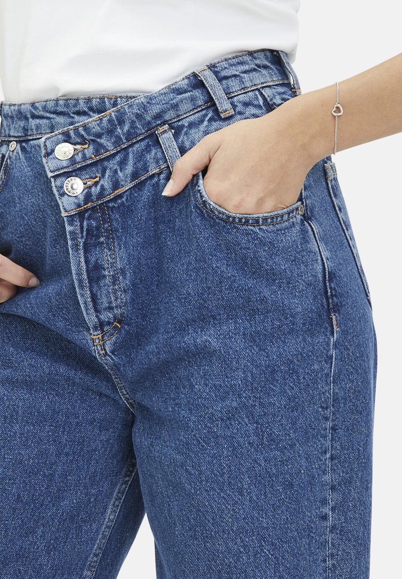 Hoge taille blauwe denim jeans met twee knopen aan de voorkant, vijf-pocket ontwerp en zichtbare stikseldetails. Zachte textuur en klassieke pasvorm.