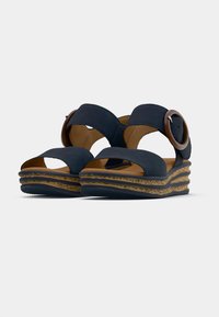 Navy blue sandals with a wide strap design, open toe, and a circular accent buckle. Features a textured wedge sole for grip and comfort.