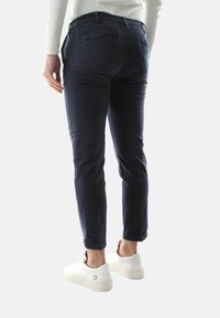 Pantaloni blu navy realizzati in tessuto leggero, con una vestibilità slim e due tasche posteriori, abbinati a sneaker bianche.
