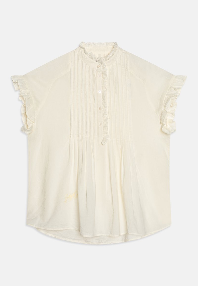 Blouse crème à manches courtes avec col et poignets volantés, plis verticaux sur le devant et fermeture à boutons au centre.