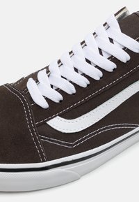 Brune semsket sneakers med hvite snører og semsket detaljer, med hvitt logodesign og kontrasterende sømmer på sålen i gummi.