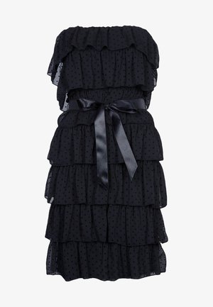 Černé šaty bez ramínek s vrstvenými volánky, vyrobené z průsvitné látky s malými puntíky, stažené v pase černou saténovou stuhou.