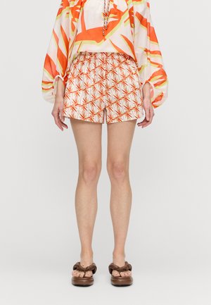 Shorts med elastisk midje, med et geometrisk palmebladmønster i oransje og hvitt. Kombinert med brune knyttesandaler.