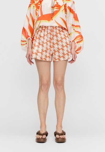 Pantaloni corti con vita elastica, caratterizzati da un motivo geometrico di foglie di palma in arancione e bianco. Abbinati a sandali marroni con nodo.