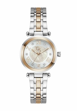 Kerek ezüst és rozéarany karóra római számokkal, gyémántórajelzőkkel, három mutatóval és láncos fém szíjjal.