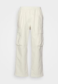 Beige cotton cargo pants with an elastic waist, two side pockets, and a logo in the upper left corner. Straight-leg design.