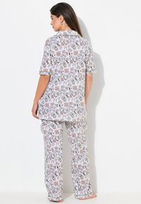 Pyzamo s květinovým vzorem z lehké látky, s krátkým rukávem, volným střihem a elastickým pasem, v kombinaci růžových a zelených odstínů.