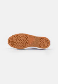 Brown rubber sole with geometric tread patterns, white midsole, and smooth edges, designed for grip and durability.