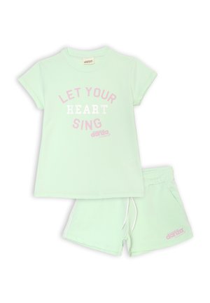 T-shirt in cotone verde menta con maniche corte, caratterizzato dalla grafica "LASCIA CHE IL TUO CUORE CANTI" in rosa e bianco. Comprende anche pantaloni corti abbinati in verde menta.