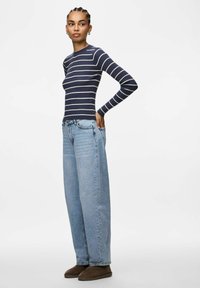 Marinblå och vitrandig, ribbad långärmad topp kombinerad med ljusblå, löst sittande jeans och bruna ankelboots. Enkelt och avslappnat outfit.