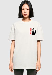Hvid bomulds t-shirt med grafisk print på brystet med teksten "NEJ, LÆG DU PÅ" i rødt og et sort spøgelse ansigt ikon. Løs pasform.