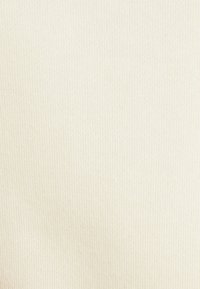 Beżowa prążkowana tkanina o delikatnej fakturze. Materiał jest miękki i rozciągliwy, odpowiedni do zastosowań w odzieży lub tapicerce.