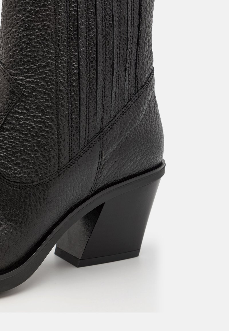 Schwarze Leder-Ankelstiefel mit strukturiertem Finish, vertikalen Linien und einem dreieckigen Blockabsatz. Verfügt über eine abgerundete Spitze und ein elegantes Design.