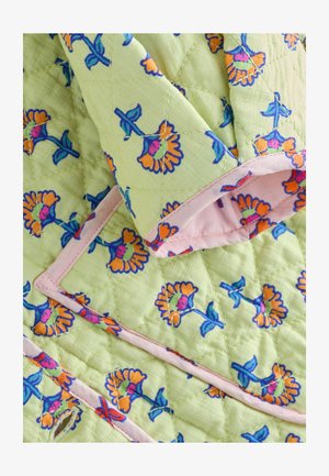 Prešiveni materijal sa svijetlo zelenom pozadinom i živopisnim narančastim i plavim cvjetnim uzorcima. Oivičen mekanim ružičastim obrubom.