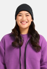 Black ribbed knit beanie worn with a purple fleece jacket featuring a zippered front and a smooth fabric texture.