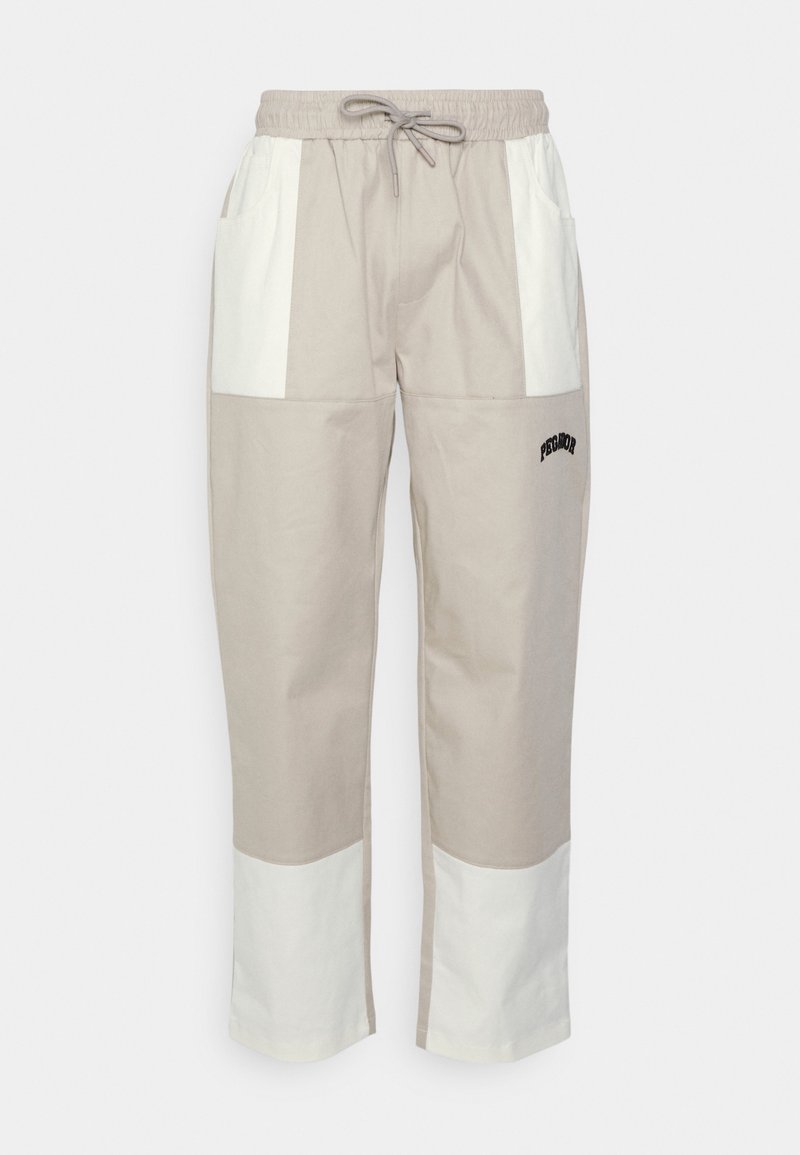 Pantalons bicolores beige et blanc avec taille élastique à cordon, poches avant et petit logo noir "PEGADOR" sur la jambe droite.