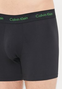 Zwarte katoenen boxershorts met een groene logo- tailleband, met een strakke pasvorm en soepele textuur. Geen zichtbare patronen of hardware-details.