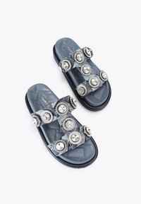 Infradito in denim con una base trapuntata blu scuro, caratterizzati da cinturini testurizzati adornati con grandi gemme circolari e accenti in argento.