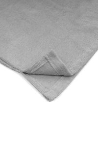 Grau handtuch mit einer weichen, strukturierten Oberfläche. Verfügt über einen gesäumten Rand und eine gefaltete Ecke, die den saugfähigen Stoff zeigt.