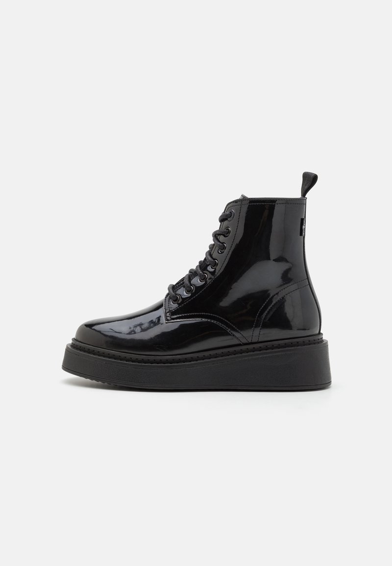 Botas de tobillo de charol negro con suela de plataforma negra gruesa, con punta redonda, cordones en la parte delantera y tirador en la parte posterior.