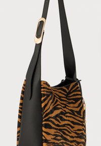 Sac à épaule en cuir noir avec un motif de rayures de tigre en marron et noir. Présente un accent en métal doré sur la sangle.