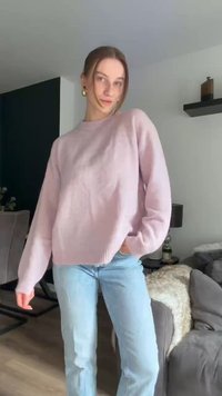 Lys pink sweater med rund halsudskæring, lange ærmer og afslappet pasform, parret med lyseblå jeans. Blød tekstur, minimalistisk design.