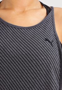 Débardeur gris avec un motif à rayures horizontales, doté d'un col rond et d'un petit logo noir, fabriqué en tissu doux et respirant.