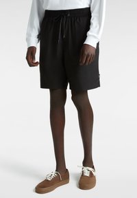 Schwarze Badeshorts mit elastischem Bündchen und Kordelzug. Das Material ist glatt und hat einen lässigen Schnitt; verfügt über ein kleines seitliches Logolabel.