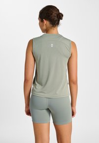 Ljusgrön ärmlös topp med slät textur och en liten central logotyp. Matchas med passande figursydda shorts. Enkel, atletisk design.