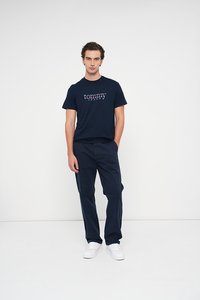 Tricou din bumbac bleu marin cu logo-ul "tommy jeans" în roșu și alb. Asortat cu pantaloni închiși la culoare și adidași albi. Design simplu, tăietură relaxată.