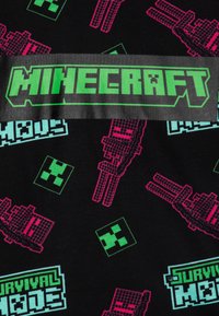 Mustista kangasta, jossa on pikselöityjä Minecraft-hahmoja ja -esineitä vaaleanpunaisena ja turkoosina. Keskellä on grafiikka, jossa lukee "MINECRAFT" vihreällä.