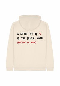 Kremkrāsas kapuci ar brīvu piegriezumu. Mugurpusē ir izcelti melni un sarkani teksti ar citātu, kā arī sarkans sirds simbols.