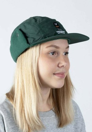 Vihreä nylonkypärä, jossa on pehmeä fleecevuori. Varustettu litteällä lierillä ja brodeeratulla kuviolla etupanelissa.