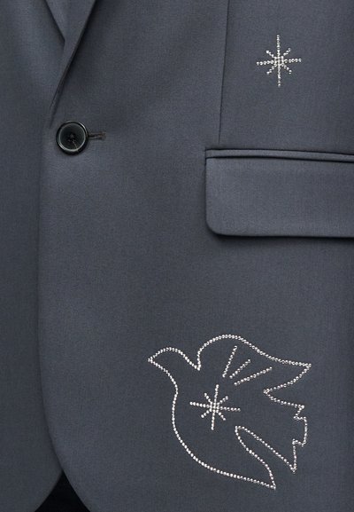 Σκούρο γκρι σακάκι με μαύρο κουμπί, τσέπη με καπάκι και σχέδια από στρας σε μορφή αστεριού και περιστεριού στο μπροστινό μέρος.