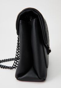 Borsa a tracolla nera in pelle con texture trapuntata, forma snella e tracolla in catena nera. Presenta una chiusura a patta e bordi morbidi e arrotondati.