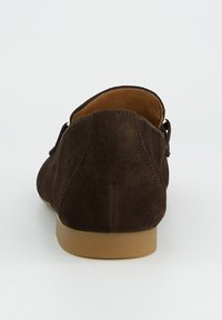 Dunkelbrauner Wildleder-Loafer von hinten gesehen, mit einer hellbraunen Sohle und gesteppten Details vor einem schlichten Hintergrund.