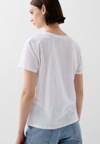 White, short-sleeve t-shirt made of lightweight fabric. Crew neck and slightly translucent texture. Simple design with no patterns or accents.