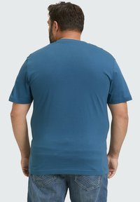 Korte mouw t-shirt in effen blauw, gemaakt van katoen, met een ronde hals en een relaxte pasvorm. Gekleed met denim jeans.