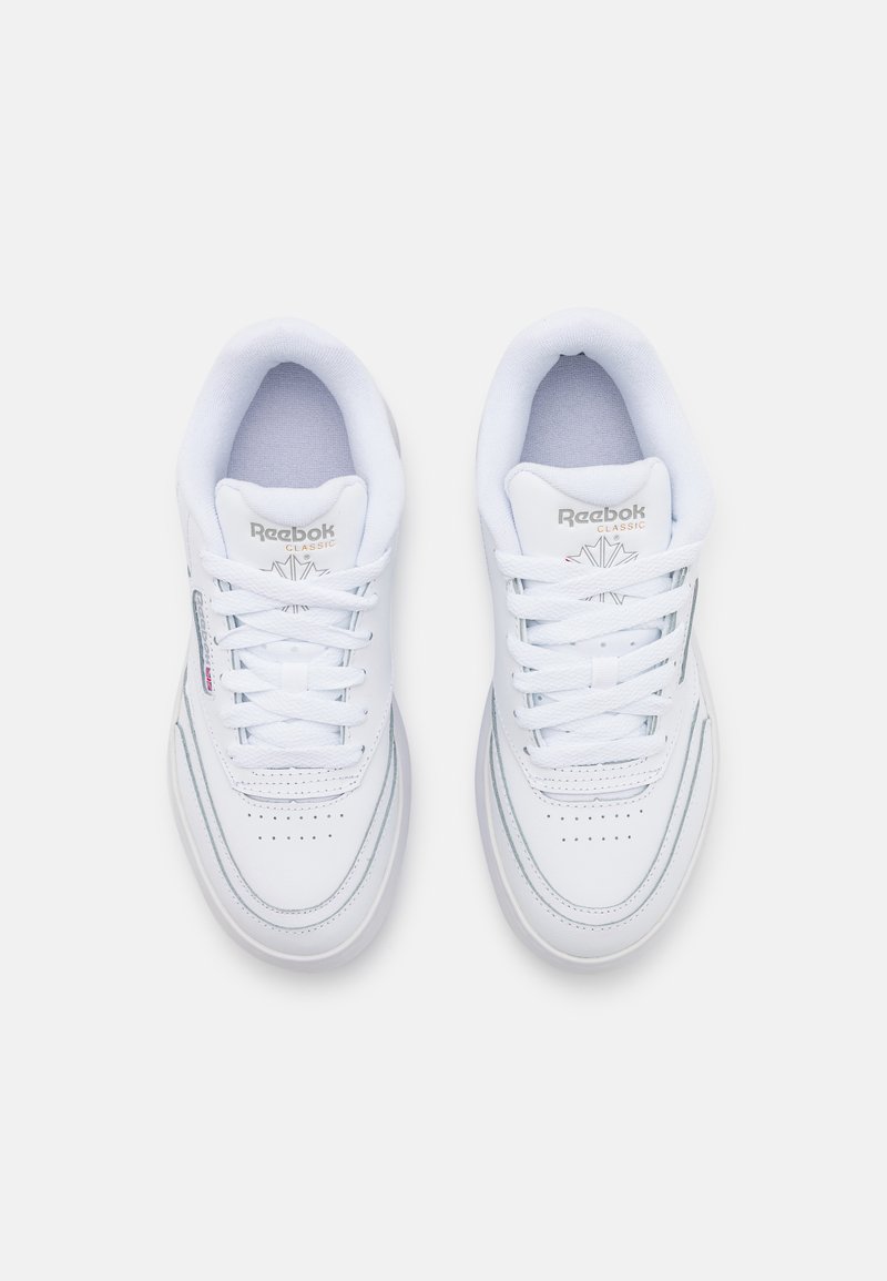 Baskets de sport blanches avec un design à lacets, texture en cuir lisse, boîte à orteils perforée et logo Reebok sur la languette.