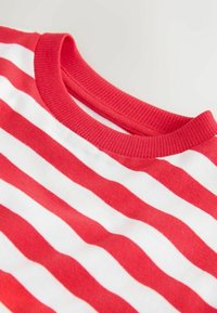 Maglietta a maniche corte a righe rosse e bianche con collo a costine, realizzata in morbido cotone con una texture liscia.