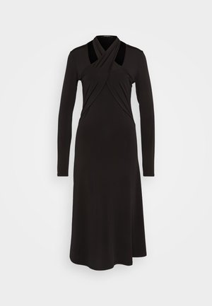 Fekete, hosszú ujjú ruha, drapált keresztezett felsőrésszel, szabott derékkal és flared szoknyával. Simá szövet, visszafogott nyakkivágás és látható fémalkatrészek nélkül.