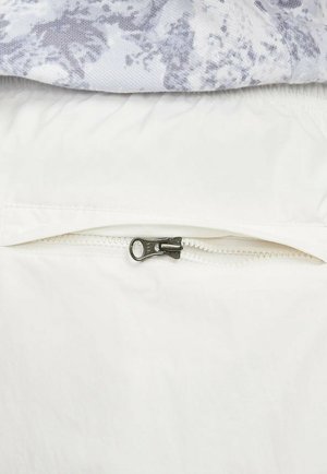 Vitt tyg med en mjuk textur och en ficka med dragkedja som har ett silverfärgat dragskon. Överlagrat grafiskt mönster i ljusgrå nyanser.