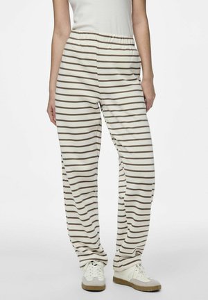 Gestreepte pyjamabroek in crème en bruin, met een elastische tailleband en een relaxte pasvorm, gedragen met witte sneakers. Ontworpen voor comfort.