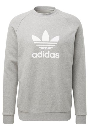 Sweat-shirt gris avec col rond, manches raglan, et un grand logo Adidas blanc avec trois bandes au-dessus et en dessous d'un motif en forme de feuille.