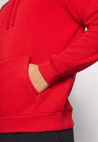 Rode hoodie met een voorzak, ribgebreide mouwen en zoom. Glad textuur, verstelbare koordjes en een relaxte pasvorm.