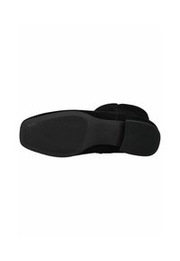 Semelle de chaussure en suède noir avec un motif de grip en caoutchouc texturé. Présente un talon plat et un design à orteil arrondi. Logo de la marque visible sur la semelle.