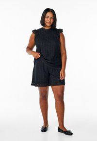 Czarna koronkowa odzież w designie bluzki i szortów, z falbaniastymi brzegami, teksturowanym wzorem i krótkimi falbanastymi rękawami.